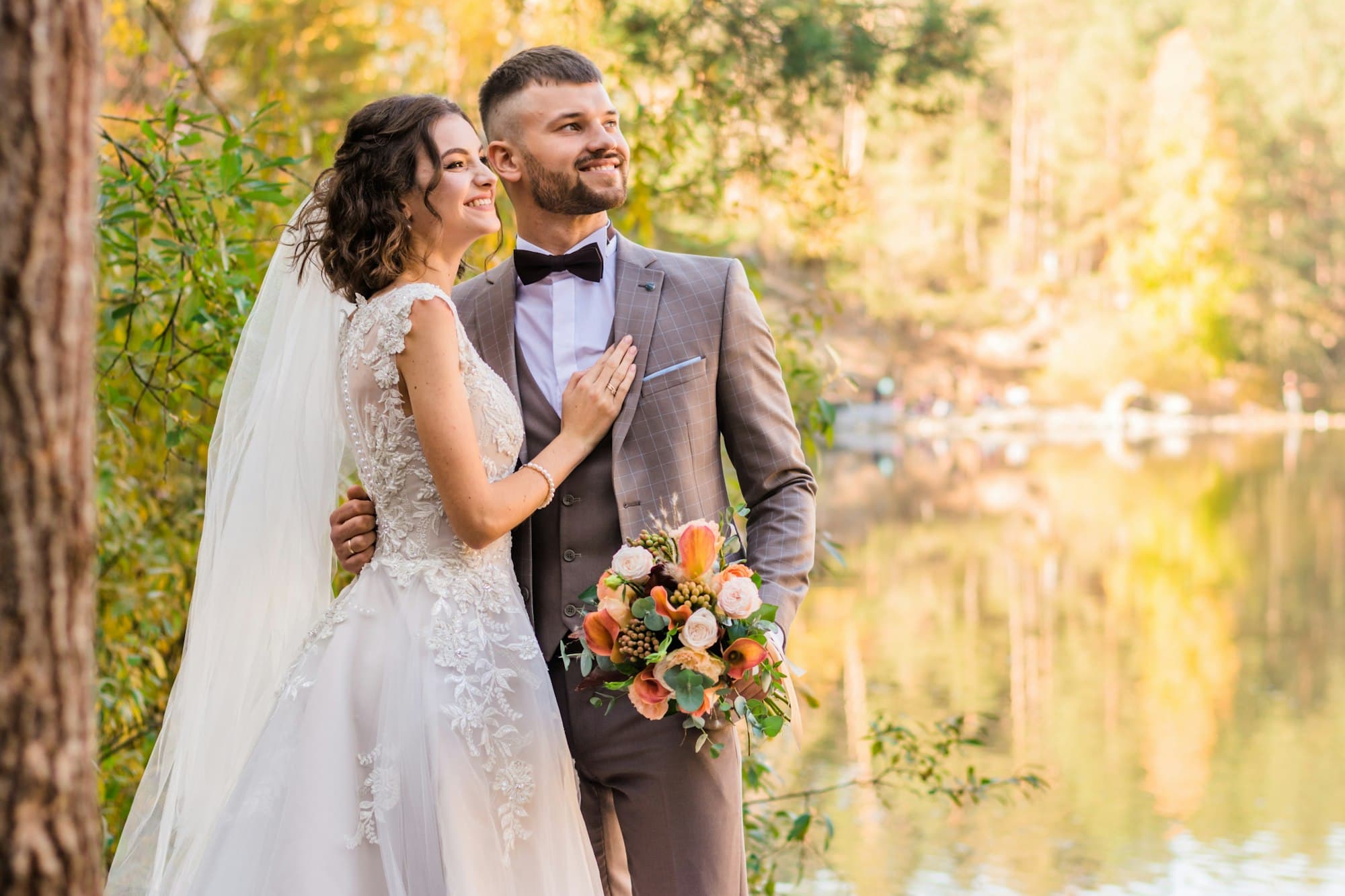 A newly married couple embraces outdoors in golden light