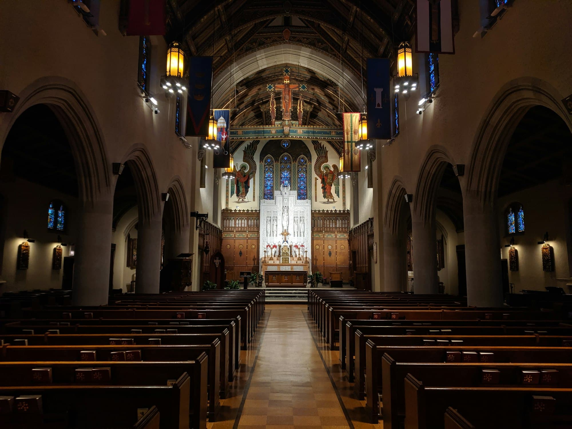 Wooden pews lead toward a sanctuary lit by stained glass